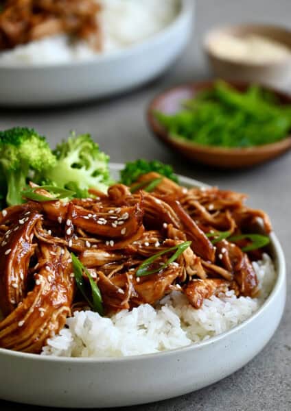 Slow cooker teriyaki chicken atop white rice in a bowl with steamed broccoli.
