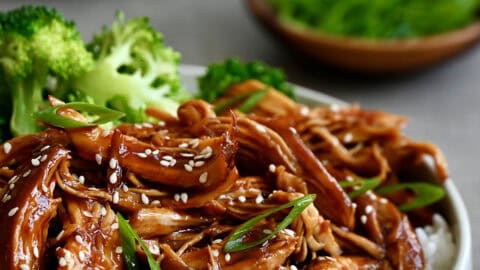 Slow cooker teriyaki chicken atop white rice in a bowl with steamed broccoli.