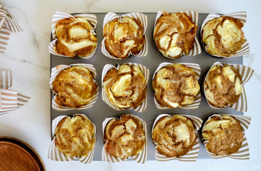 A top-down view of a muffin tin containing freshly baked Cream Cheese Pumpkin Muffins