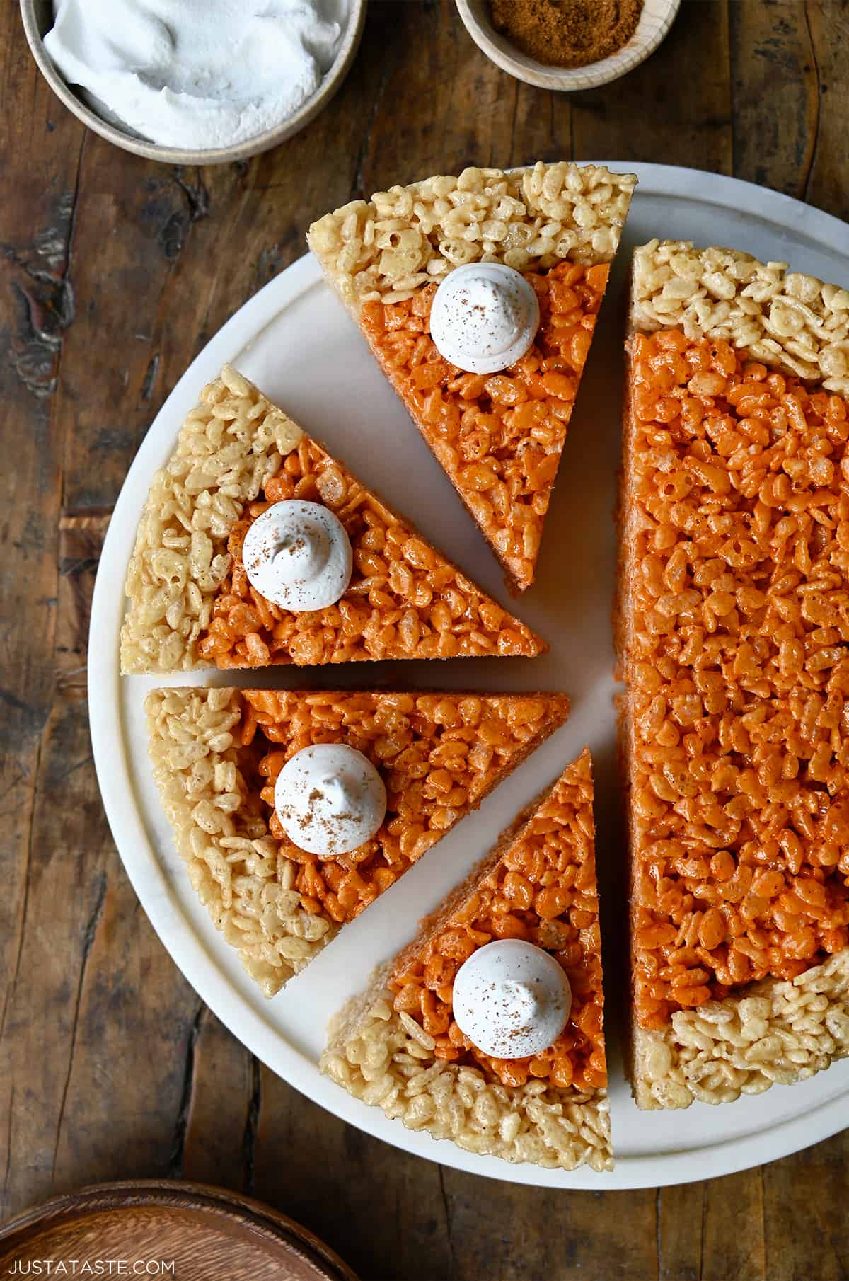 Pumpkin Rice Krispie treats cut into pie wedges and topped with a dollop of whipped cream.