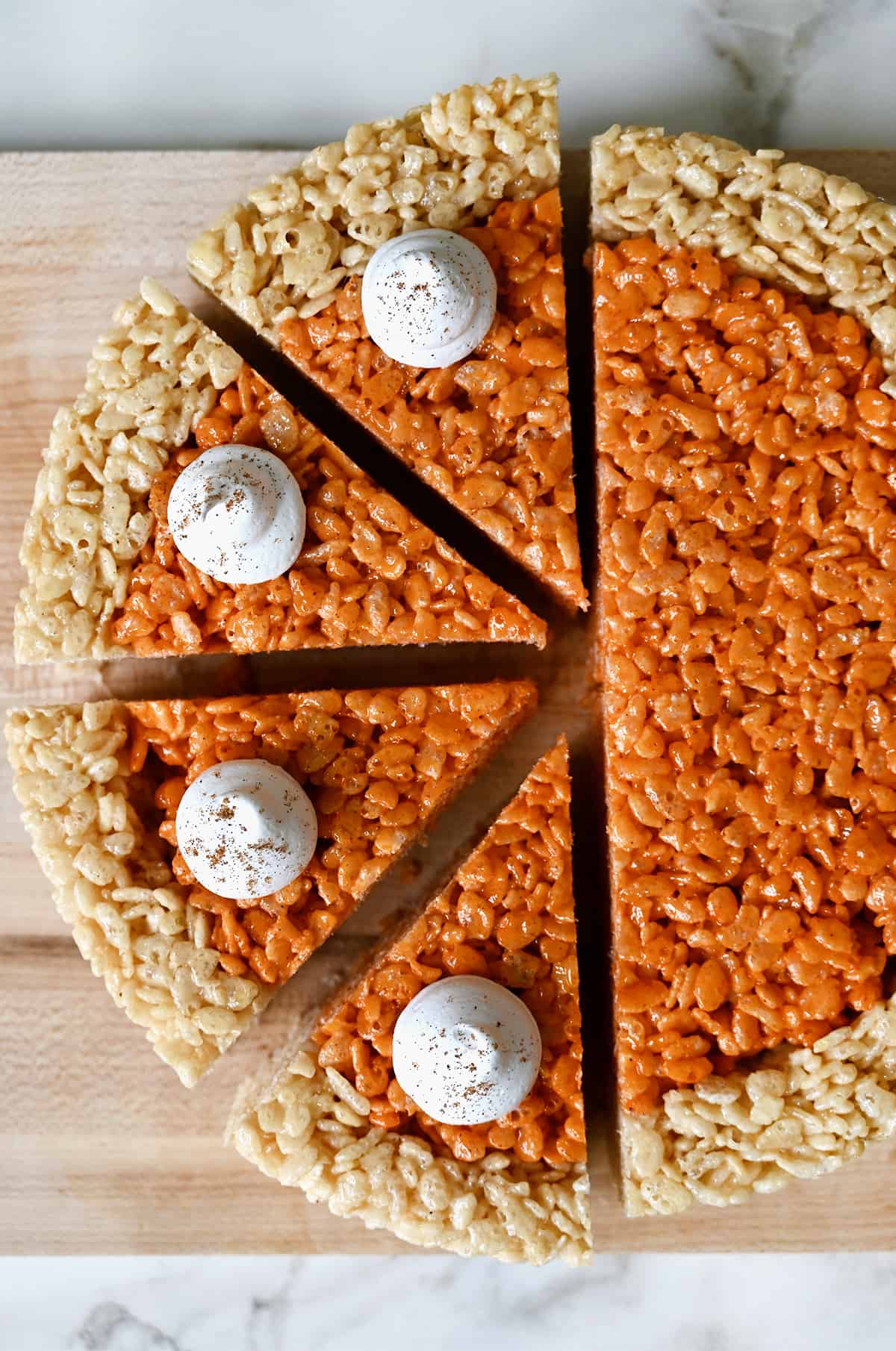 Pumpkin-flavored marshmallow treats topped with dollops of whipped cream and sliced into pie wedges.