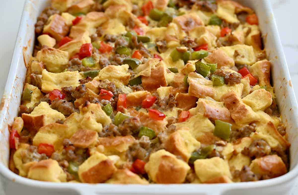 A baked breakfast casserole with cubed bread and cheddar cheese.