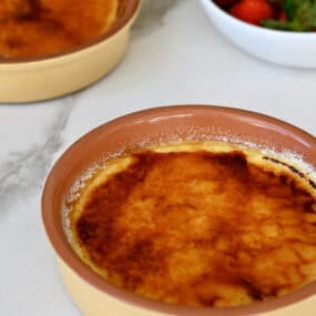 Two ramekins containing creme brulee cheesecakes with a burnt sugar topping.