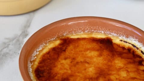 Two ramekins containing creme brulee cheesecakes with a burnt sugar topping.