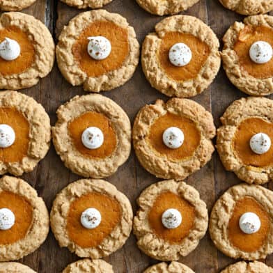 Rows of pumpkin cheesecake cookies topped with a dollop of whipped cream.