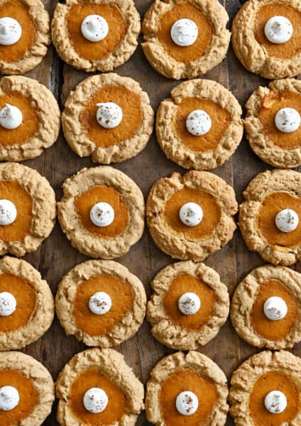 Rows of pumpkin cheesecake cookies topped with a dollop of whipped cream.