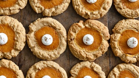 Rows of pumpkin cheesecake cookies topped with a dollop of whipped cream.