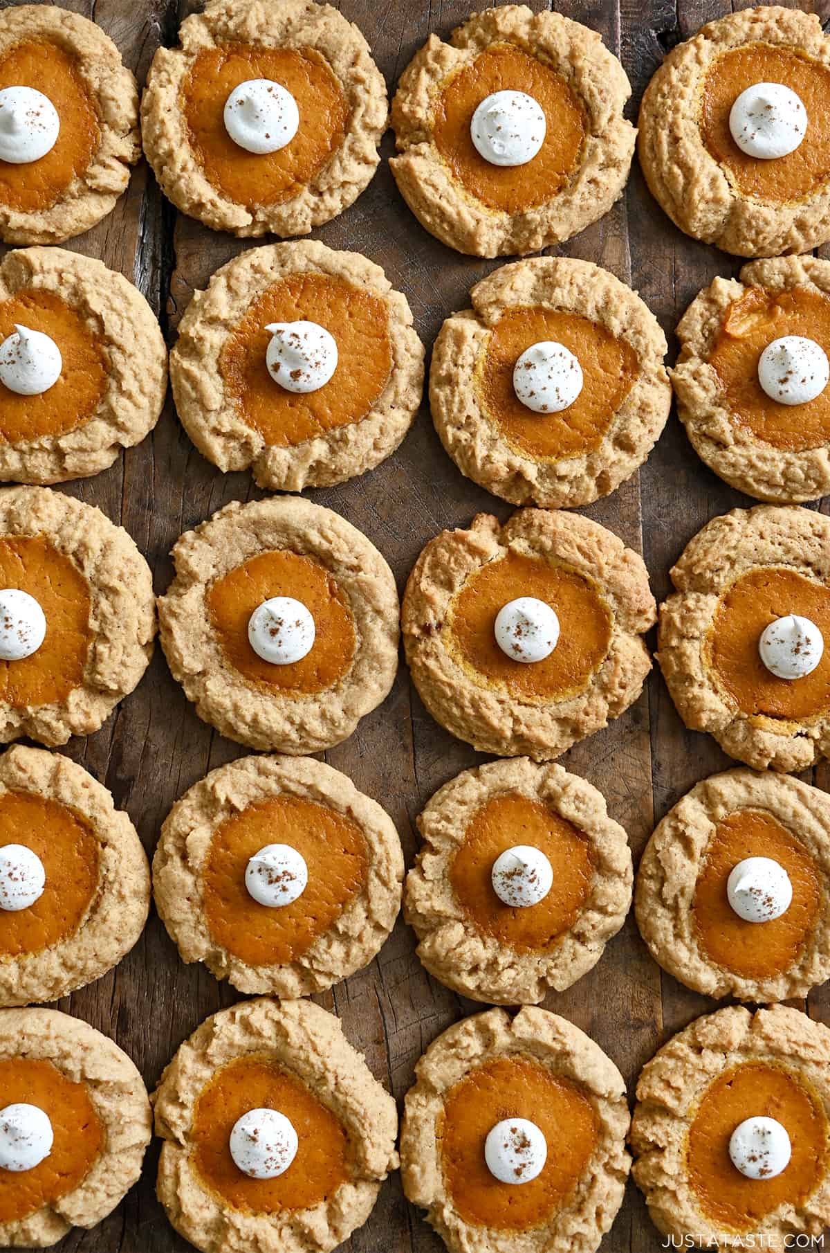Rows of pumpkin cheesecake cookies topped with a dollop of whipped cream.