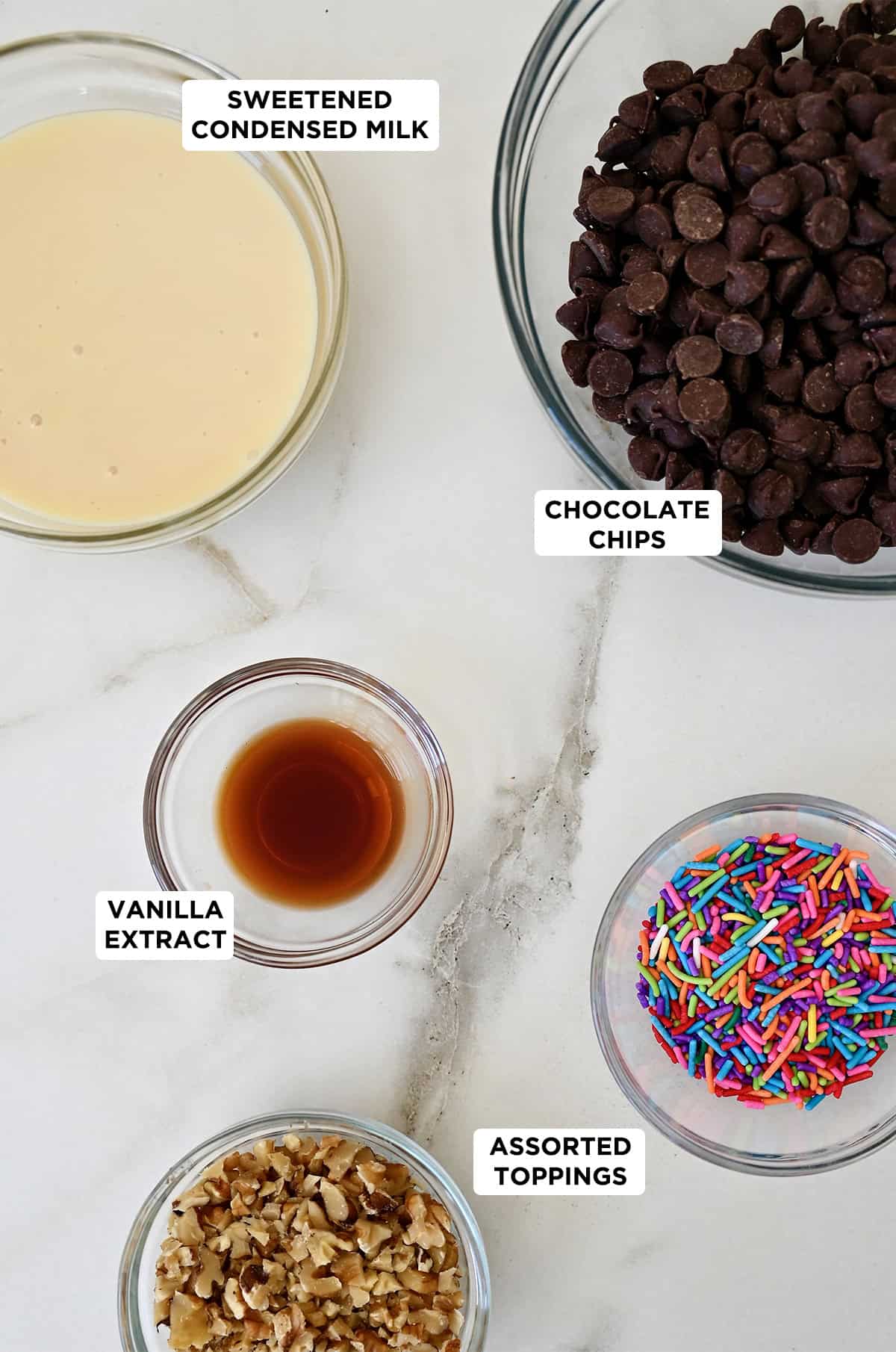 Microwave fudge ingredients in glass bowls: sweetened condensed milk, chocolate chips and vanilla extract.
