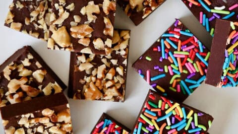 Homemade microwave fudge topped with rainbow sprinkles and chopped walnuts on a white plate.