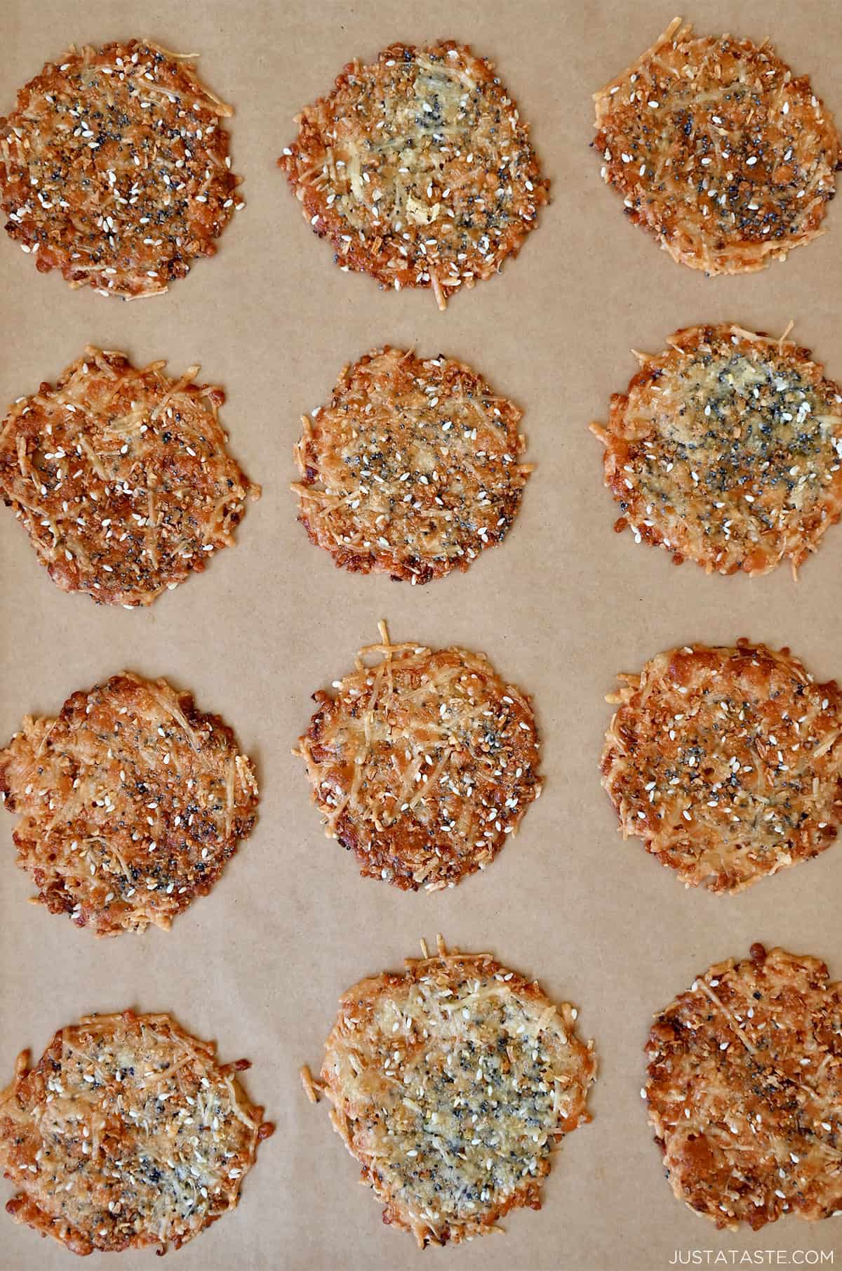 Golden brown Parmesan cheese crisps topped with everything seasoning cooling on a baking sheet.