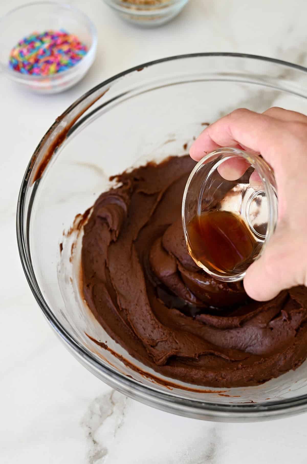 Adding vanilla extract to chocolate fudge in a bowl.