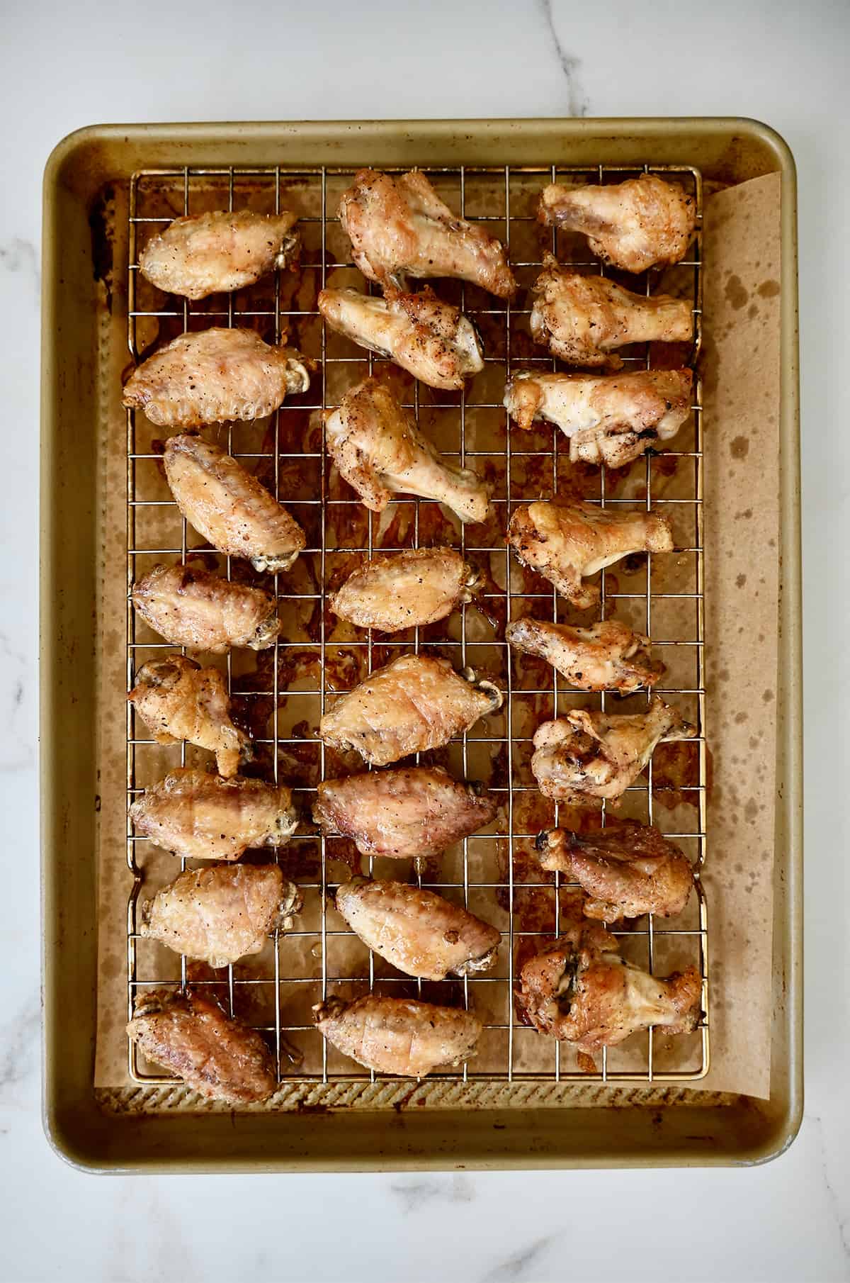 Crispy baked wings on a baking rack atop a rimmed baking sheet lined with parchment paper.