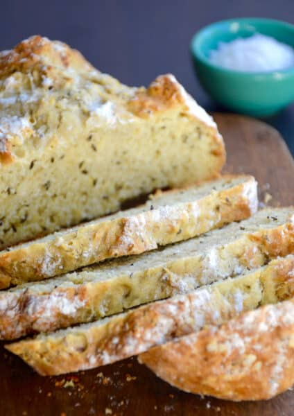 Half a loaf of homemade soda bread with caraway seeds sliced on a cutting board.