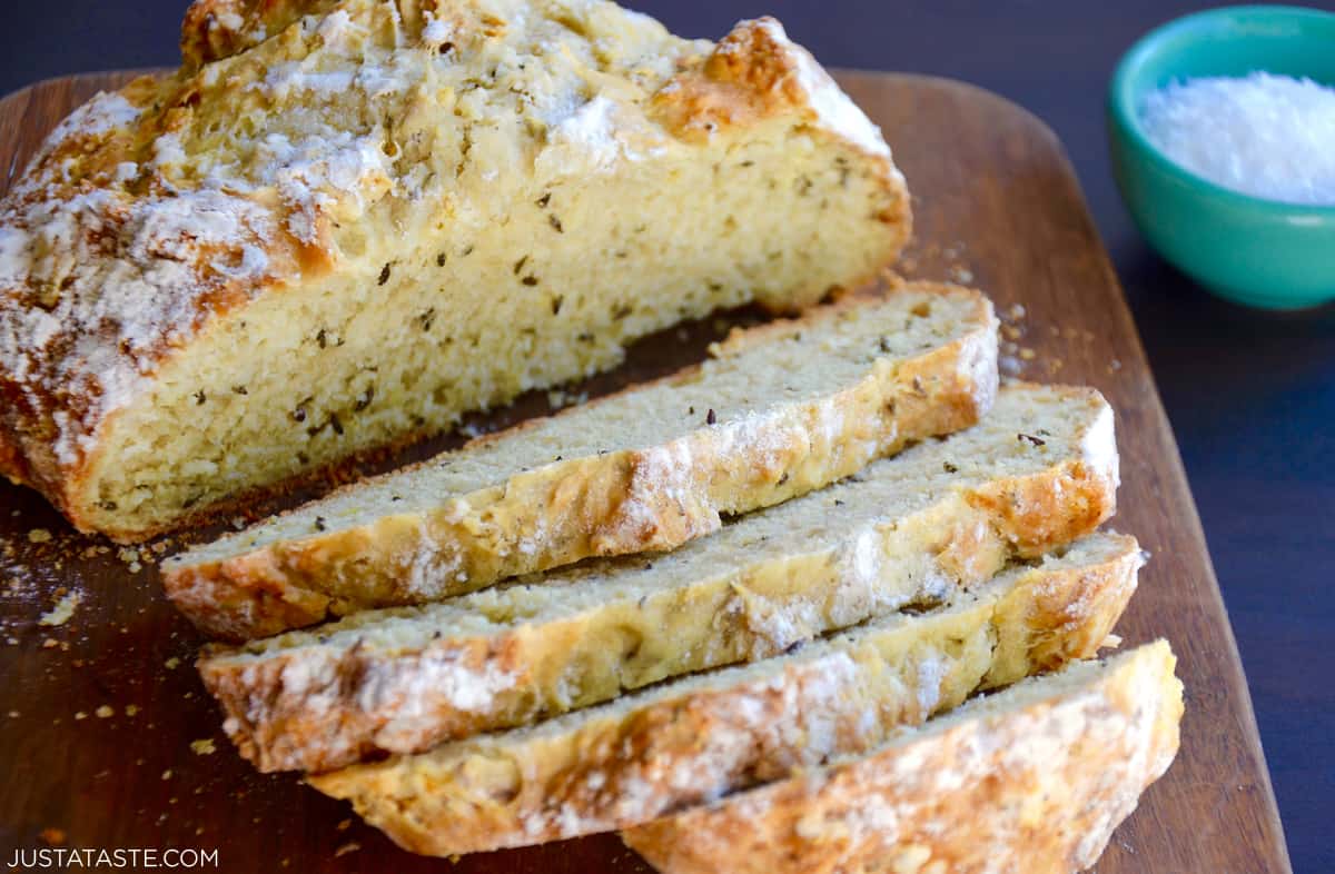 Easy homemade soda bread with caraway seeds sliced into four slices on a cutting board.