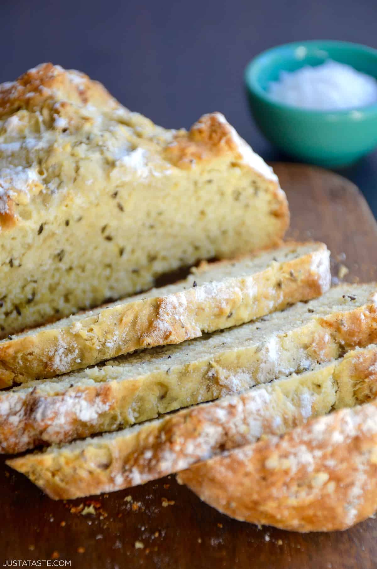 Half a loaf of homemade soda bread with caraway seeds sliced on a cutting board.