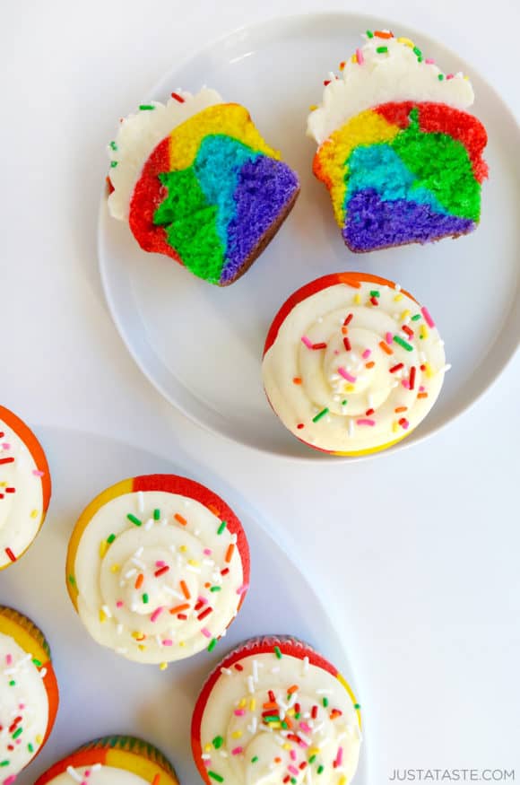 Top down view of rainbow cupcake cut in half with more cupcakes on another plate