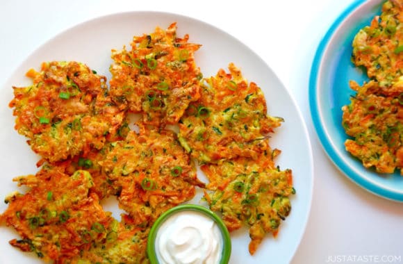 Plate containing Quick and Crispy Vegetable Fritters next to small green ramekin with sour cream