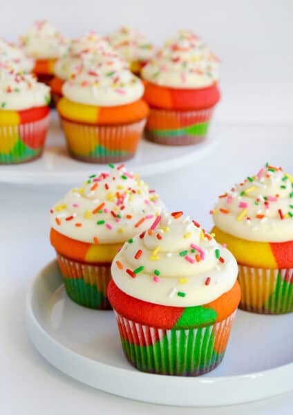 Rainbow Cupcakes with Buttercream Frosting and sprinkles on white plate.
