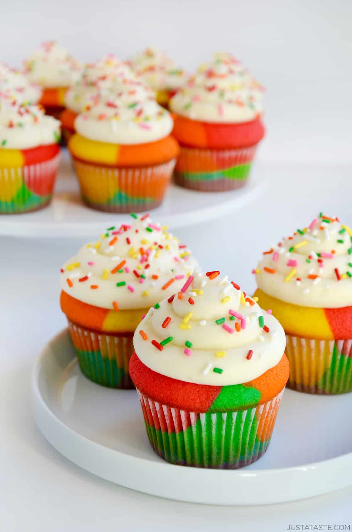 Rainbow Cupcakes with Buttercream Frosting and sprinkles on white plate.