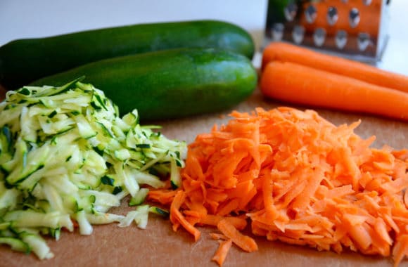 Shredded zucchini and shredded carrots on cutting board 