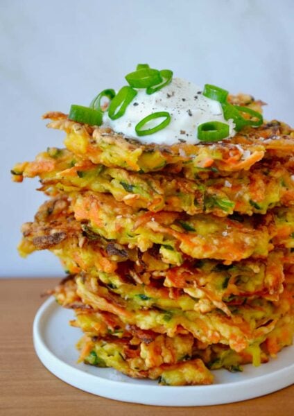 Stack of Quick and Crispy Vegetable Fritters topped with sour cream and sliced scallions