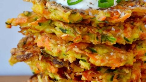 Stack of Quick and Crispy Vegetable Fritters topped with sour cream and sliced scallions