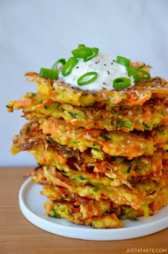Stack of Quick and Crispy Vegetable Fritters topped with sour cream and sliced scallions