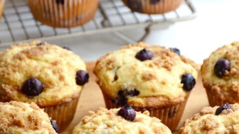 Blueberry muffins with crumb topping on a wood serving platter.