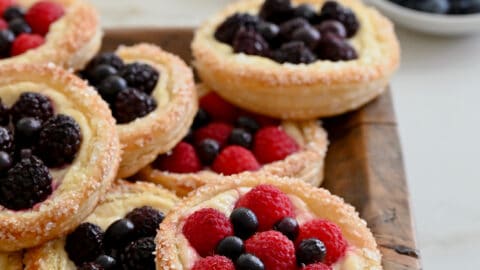 Fruit and Cream Cheese Breakfast Pastries on a wood serving platter next to two glasses of orange juice