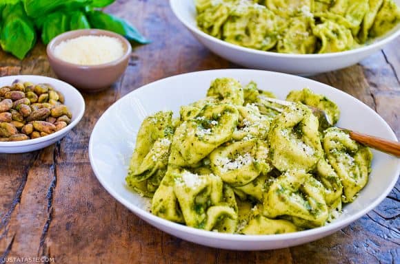 Two bowls filled with Pistachio Pesto Tortellini with fresh basil in the background