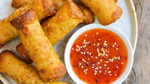 A plate of chicken egg rolls with sweet-and-sour dipping sauce