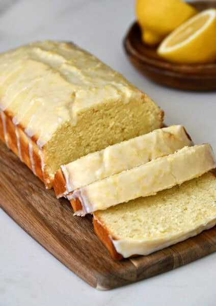 Glazed lemon loaf slices on a small wood cutting board.