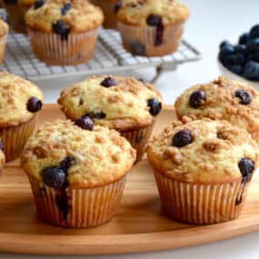 Blueberry crumble muffins on a wood serving plate.