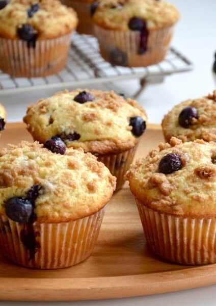 Blueberry crumble muffins on a wood serving plate.