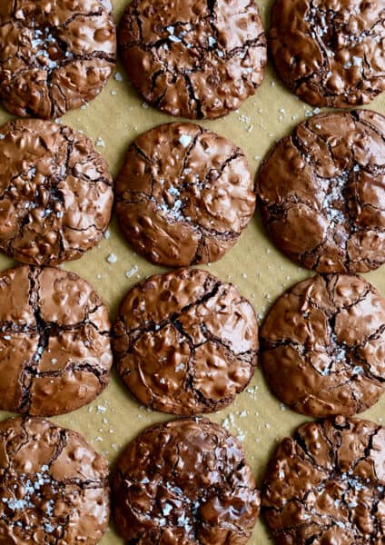 A top-down view of Flourless Chocolate Cookies dusted with large-flake sea salt