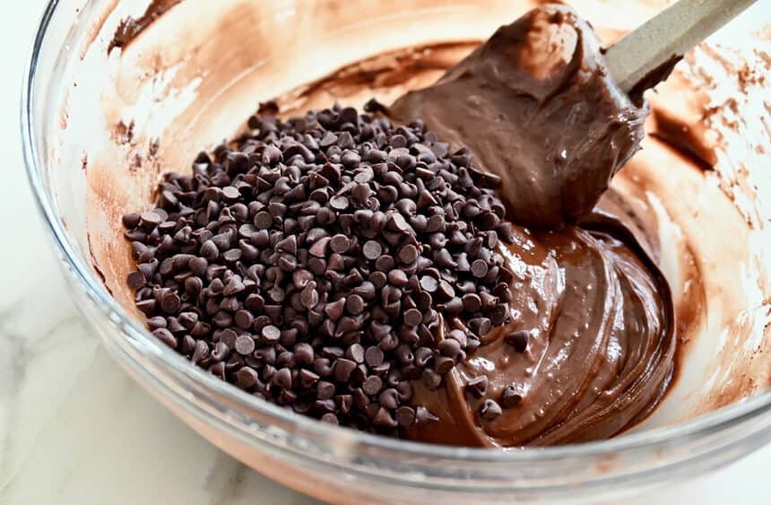 A clear bowl containing chocolate batter with chocolate chips