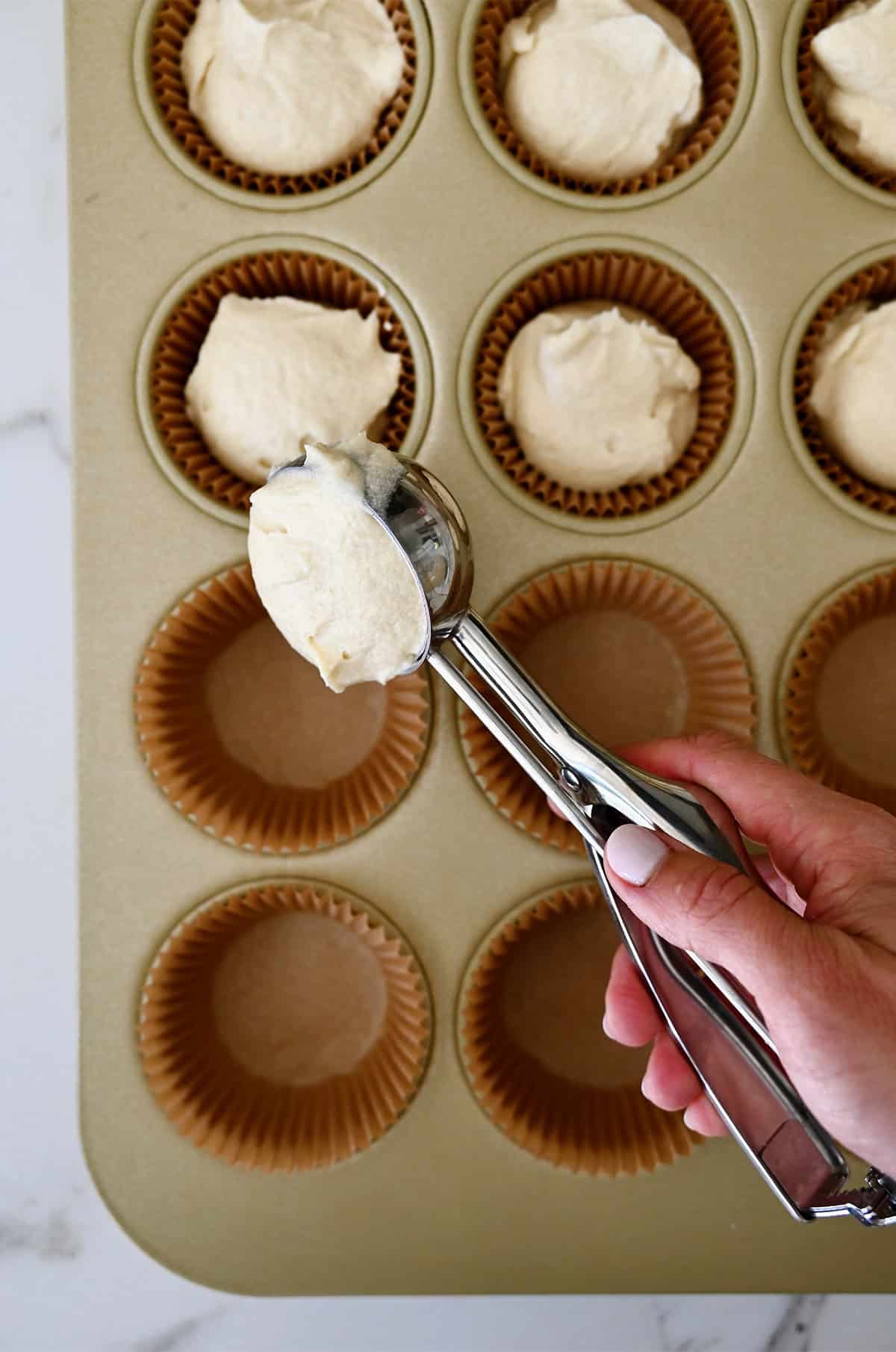 Filling cupcake liners 2/3 full using a cookie scoop.