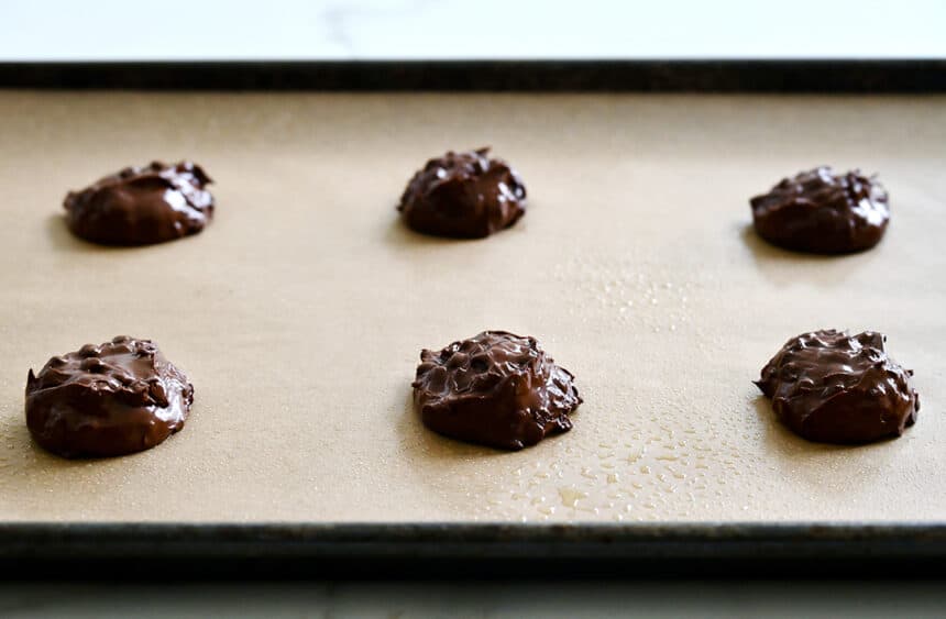 Unbaked scoops of dough atop a parchment paper-lined baking sheet