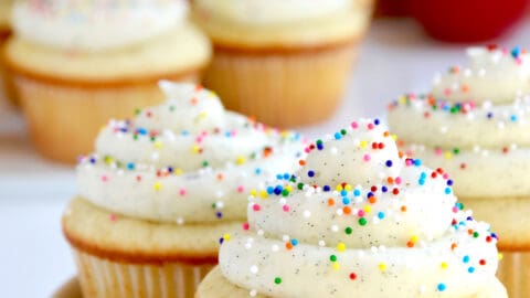 White plate containing Vanilla Bean Cupcakes with Buttercream Frosting and rainbow sprinkles