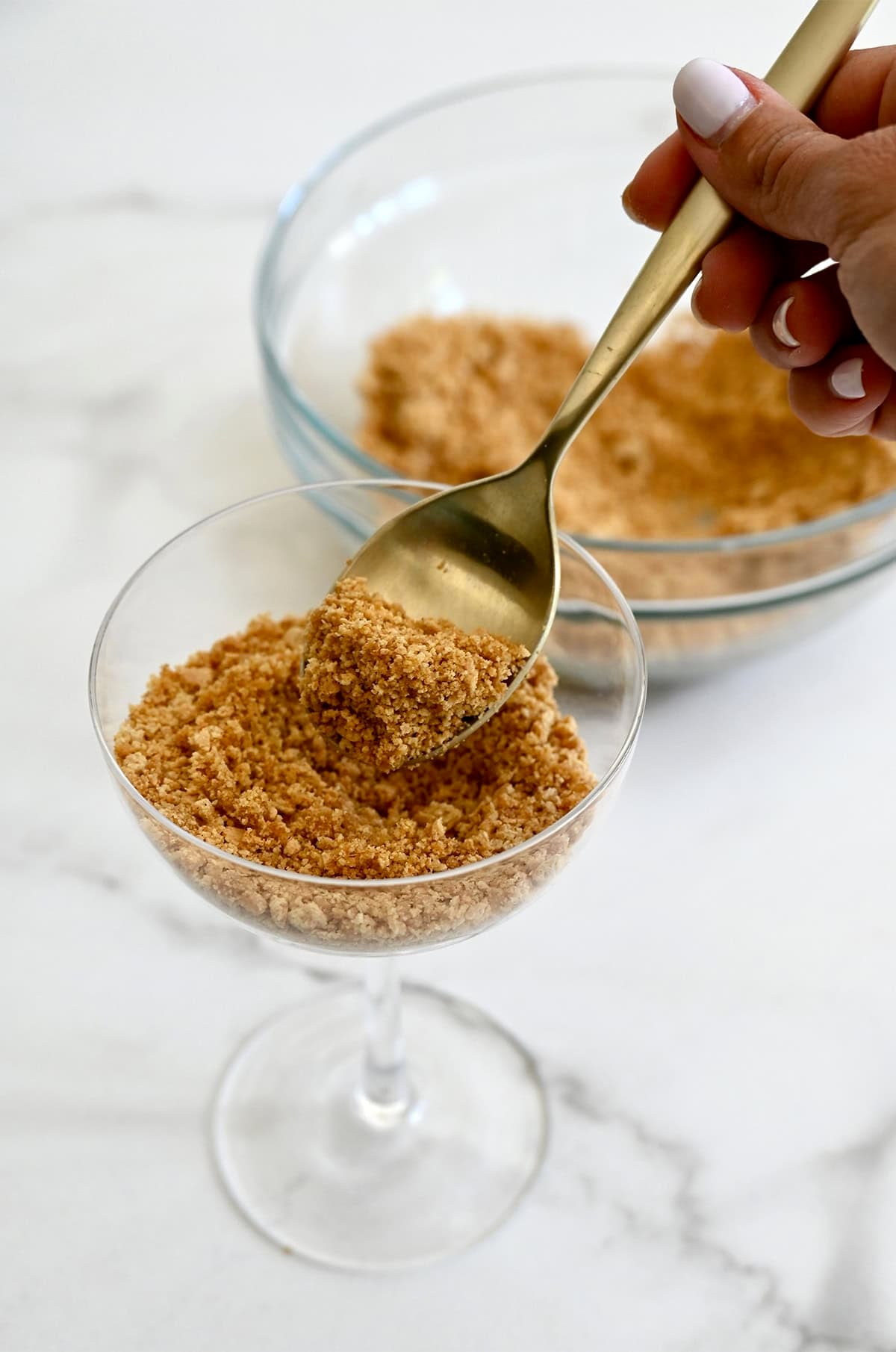 Adding buttery graham cracker crust to a cocktail glass.