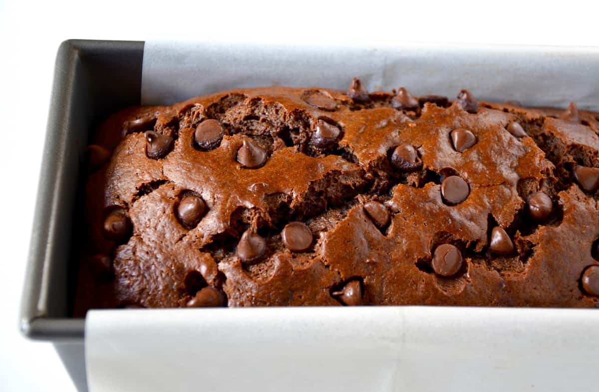 Chocolate banana bread with chocolate chips in a bread pan lined with parchment paper.