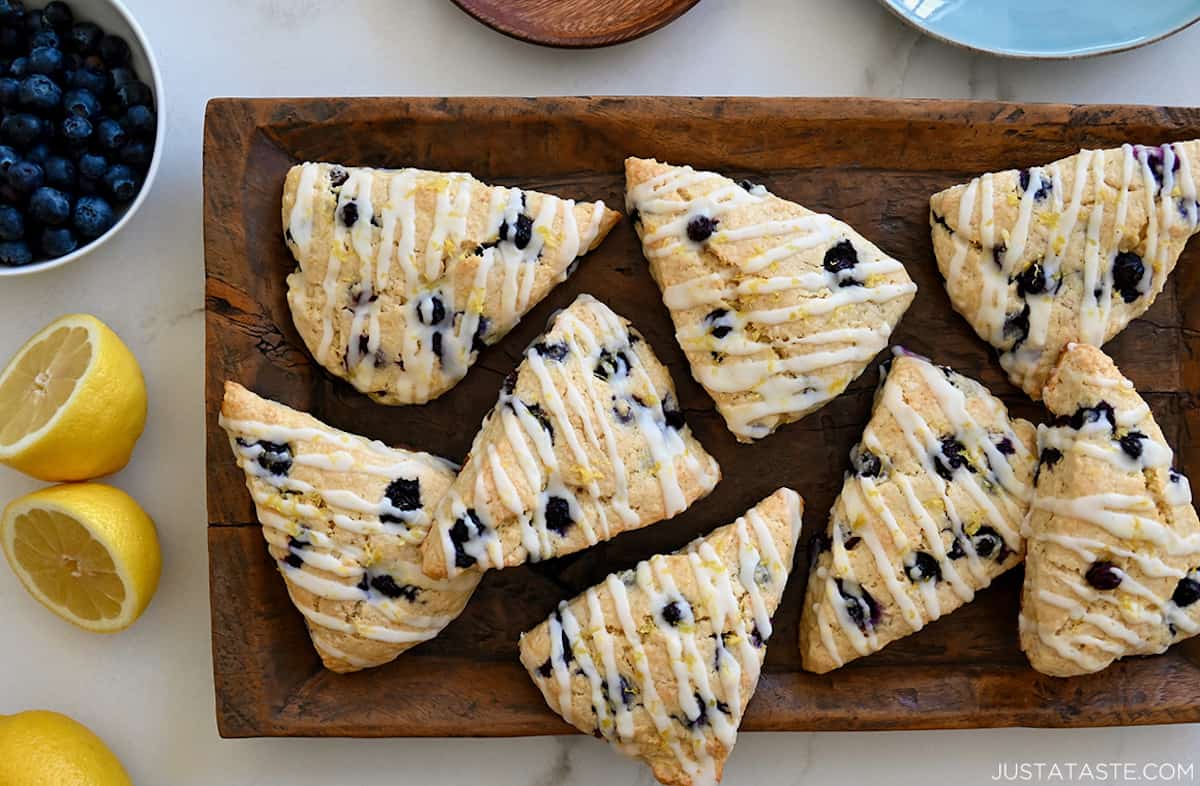 A top-down view of Glazed Lemon Blueberry Scones on a wood serving platter.