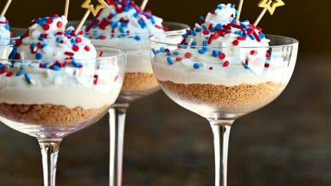 Fourth of July no-bake cheesecake cocktail cakes with red, white and blue sprinkles.