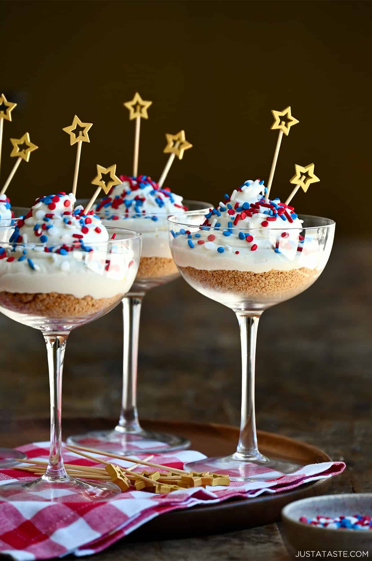 Fourth of July no-bake cheesecake cocktail cakes with red, white and blue sprinkles.