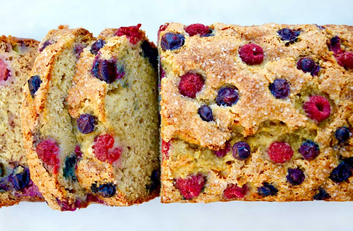 A loaf of banana bread studded with raspberries and blueberries.