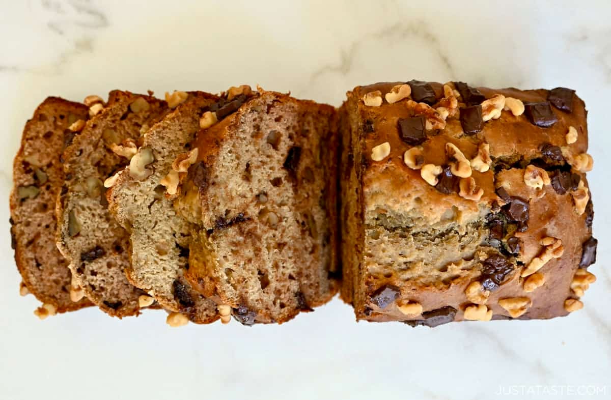 A golden brown loaf of cottage cheese banana bread studded with chocolate chunks and chopped walnuts.