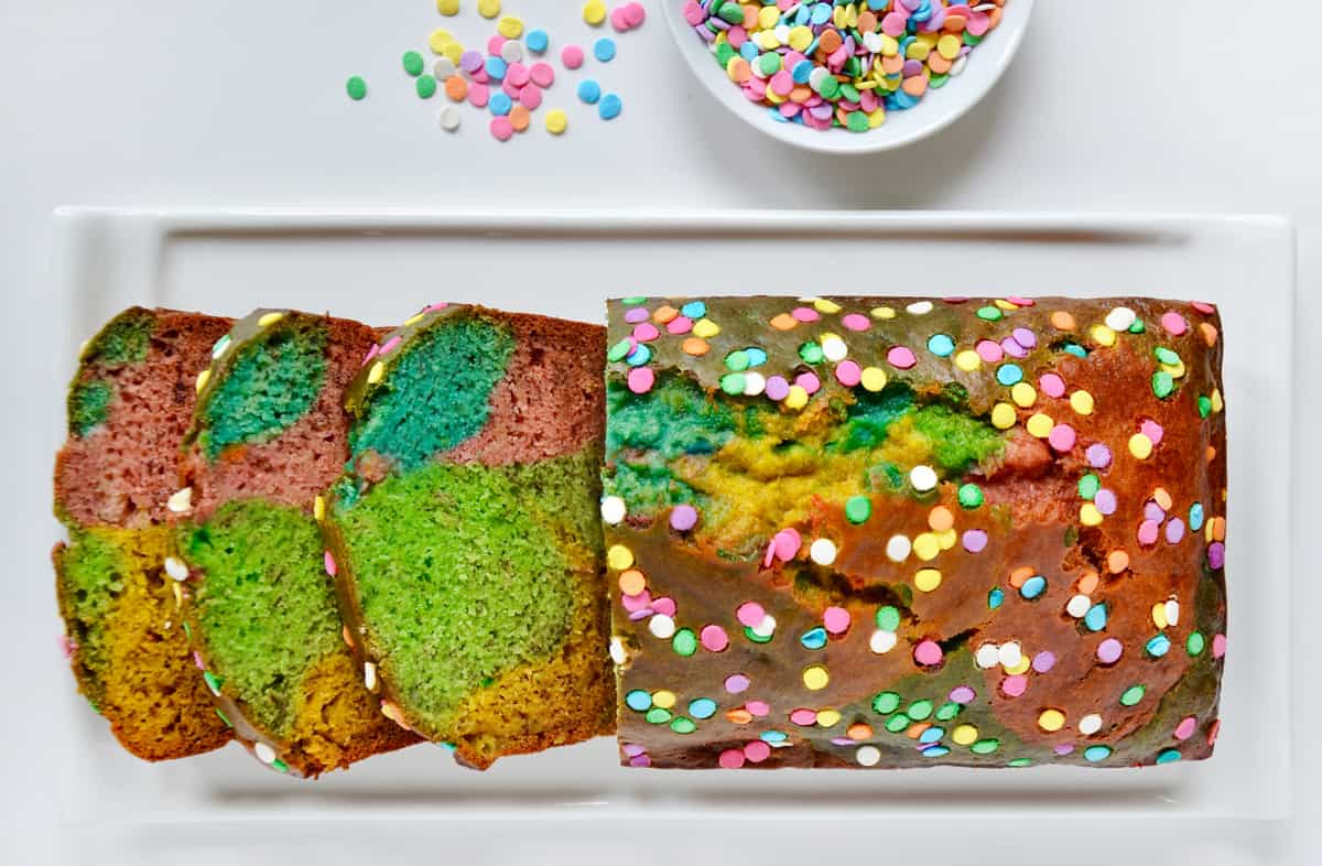 A multi-colored loaf of banana bread studded with rainbow sprinkles.