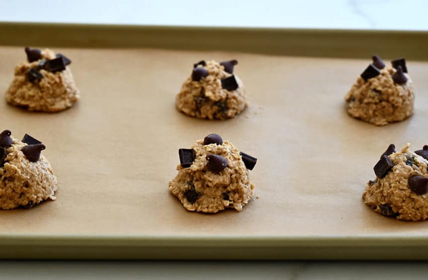 Scooped cookie dough on a parchment paper-lined baking sheet