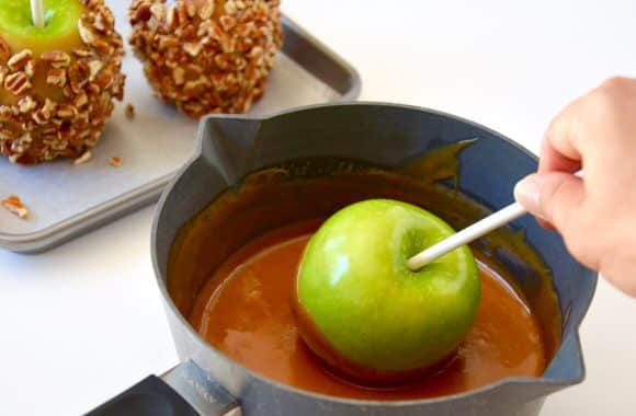 Dipping apple in caramel sauce